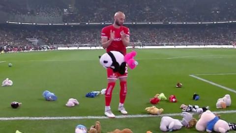 A footballer standing in front of a falling soft panda toy