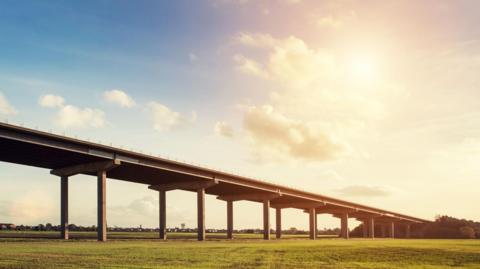 An artistic stock photograph of the Ouse Bridge, with fields and sunshine.