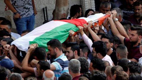 Mourners carry the body of Palestinian woman Aisha Rabi, who was killed when a stone hit her car in the occupied West Bank on 12 October