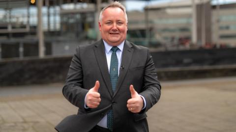 Darren Millar wearing a suit with his thumbs up