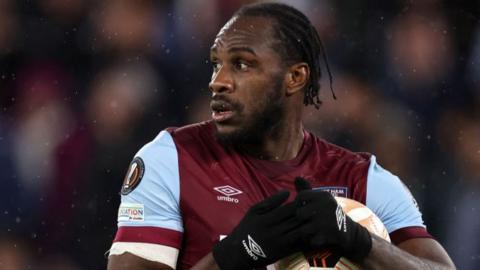 West Ham striker Michail Antonio holds a ball to his chest