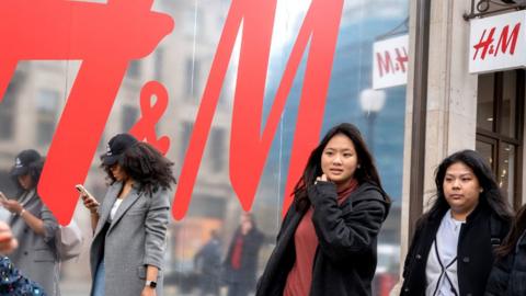 Members of the shopping public pass beneath the H&M logo outside their shop at Oxford Circus, on 30 March 2023, in London, England