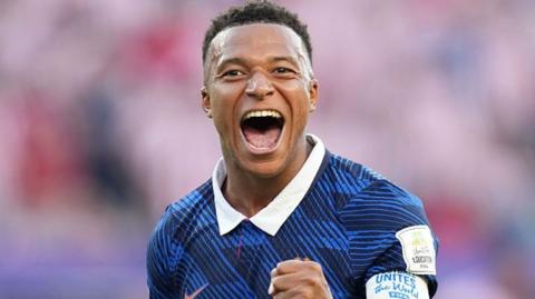 Kylian Mbappe with wide open mouth and happy face in France's blue football shirt with white collar