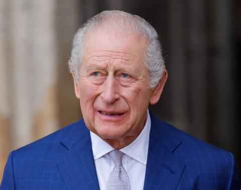 King Charles seen wearing a blue suit, with a white shirt and tie 