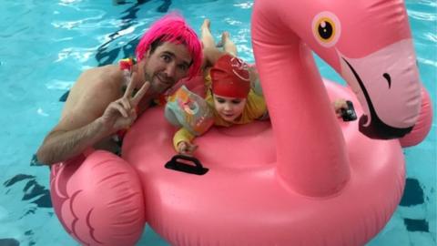 A child with Dad on a flamingo inflatable