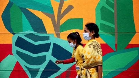 Indian people walk past the graffiti depicting "The story of coronavirus COVID19 pandemicâ€™"to create awareness among people in Bangalore,