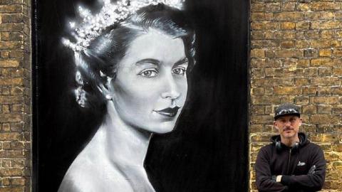 Dan Kitchener standing next to his street art tribute to Queen Elizabeth II