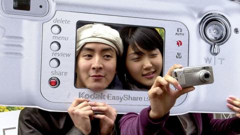 People posing with giant cardboard Kodak camera