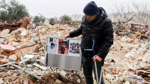 A Palestinian man holds up the remains of a refrigerator destroyed when Israeli authorities demolished a home in the Sheikh Jarrah neighbourhood of East Jerusalem on 19 January 2022