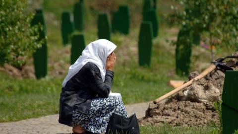 A Bosnian woman prays at the memorial for the victims of the Srebrenica massacre
