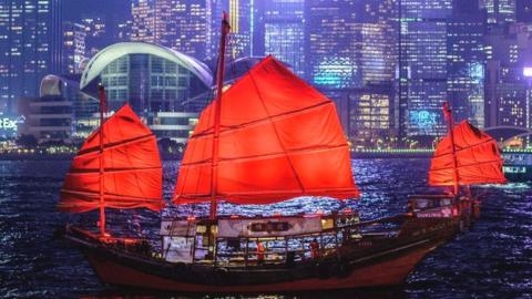 A traditional wooden tourist junk boat sails in the waters of Victoria Harbour in Hong Kong.