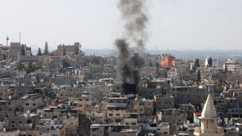 Smoke billows over Tulkarm refugee camp, West Bank. It is a hazy, sunny day. 