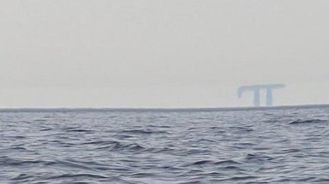 A picture of a Fata Morgana in the distance taken from a boat. 