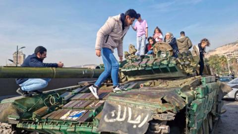 People visit an army tank belonging to the toppled Syrian government, in Damascus, on December 10, 2024