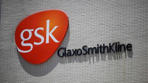 Sign saying GSK GlaxoSmithKline on a white wall