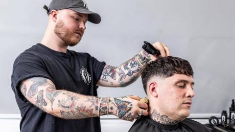 Barber Jake Cox cuts a client's hair 