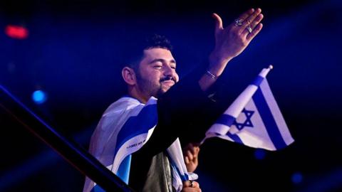 Noam Bettan, carrying an Israeli flag, waves to the audience at Vienna's Wiener Stadthalle after the first semi-final on Tuesday 12 May 2026