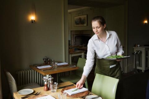 Woman wearing apron setting table in a restaurant