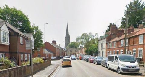 A picture looking down the road towards a church.  Terraced properties are on both sides of the road.