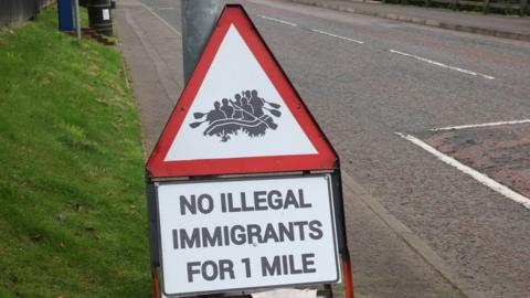 Red sign saying "NO ILLEGAL IMMIGRANTS FOR 1 MILE"