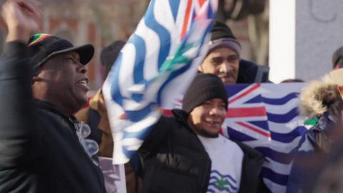 A group of people protest in central London. Some are holding the flag of the British Indian Ocean Territory.