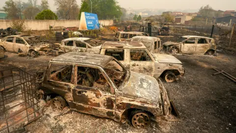 Burned out cars sit in a car park after a wildfire burned the area in Casavieja, Avila, taken on Monday