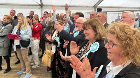 A crowd of Reform UK supporters cheering 