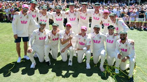 The Australia team celebrate winning the Ashes with a glass trophy version of the urn
