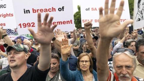 Members of South Africa's white Afrikaans population are seen with their arms raised during a protest outside the US embassy in South Africa