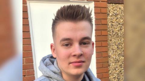 Kylan Mulligan wearing a grey hoodie outside a brick building