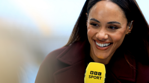 Alex Scott holding a BBC Sport microphone