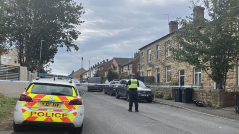 A police car and a police officer at a cordoned off house