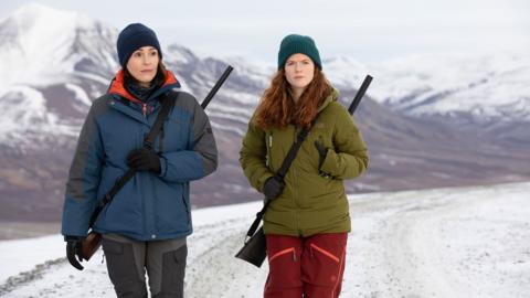 Two people walking in the snow.