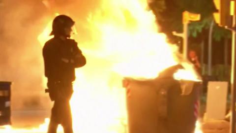 A riot policeman stands guard near a burning barricade in Barcelona