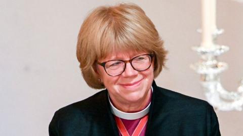 Sarah Mullally pictured smiling. She has short blonde hair and is wearing glasses. 