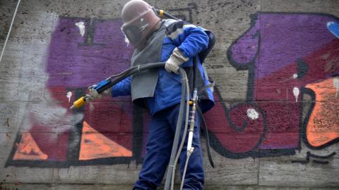 A worker removes a graffiti with a sandblaster from a wall on April 4, 2013 in Munich, southern Germany.