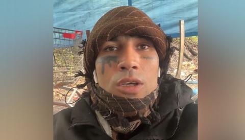 Fayaz Khan looking at the camera. He is wearing a green bandana and a green coat.