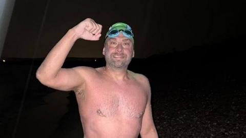 Mr David in France wearing red swim wear after finishing English Channel crossing.