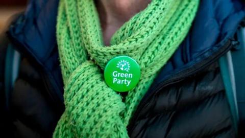 Unkown woman wearing a Green Party badge on a green scarf