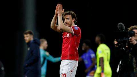 Wrexham midfielder Ollie Rathbone applauds fans