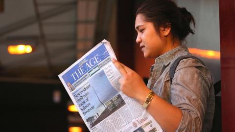A commuter reads The Age's first compact edition newspaper at Flinders Street Station on March 4, 2013 in Melbourne, Australia