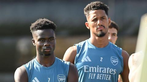 Bukayo Saka (left) and William Saliba in blue-green Arsenal vests