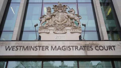 The exterior of Westminster Magistrates’ Court shows the building’s name in large letters beneath a stone coat of arms.