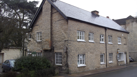 A cottage on Sheep Street in Cirencester houses the war time museum. The cottage is built from beige stones with white windows.