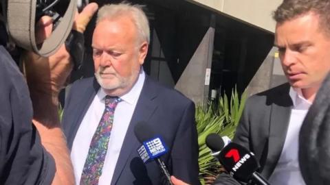 Former NHS boss surrounded by reporters as he arrived in court last July