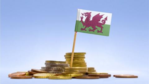 A pile of coins surround a Welsh flag