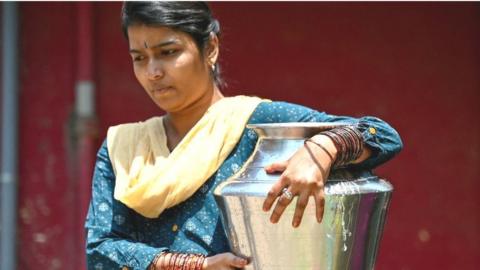 A woman carries a can of water filled from a municipal tap, amid an ongoing water crisis in Bengaluru on March 7, 2024.