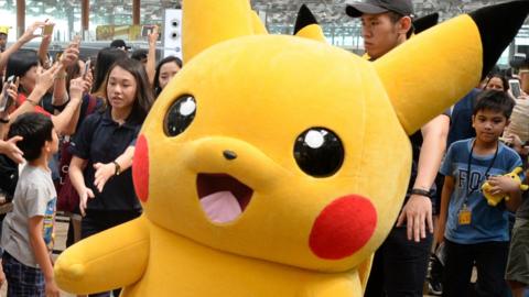 Fans gather to watch the Pokemon Go virtual reality game mascot Pikachu parade during a promotional event at the Changi International airport terminal in Singapore on November 18, 2016