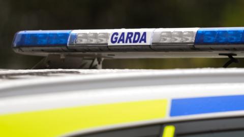 The top of a white, blue and yellow garda (Irish police) car with sign