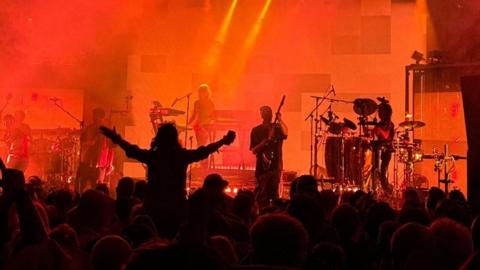 A crowd watching Faithless with Max on guitar near the front